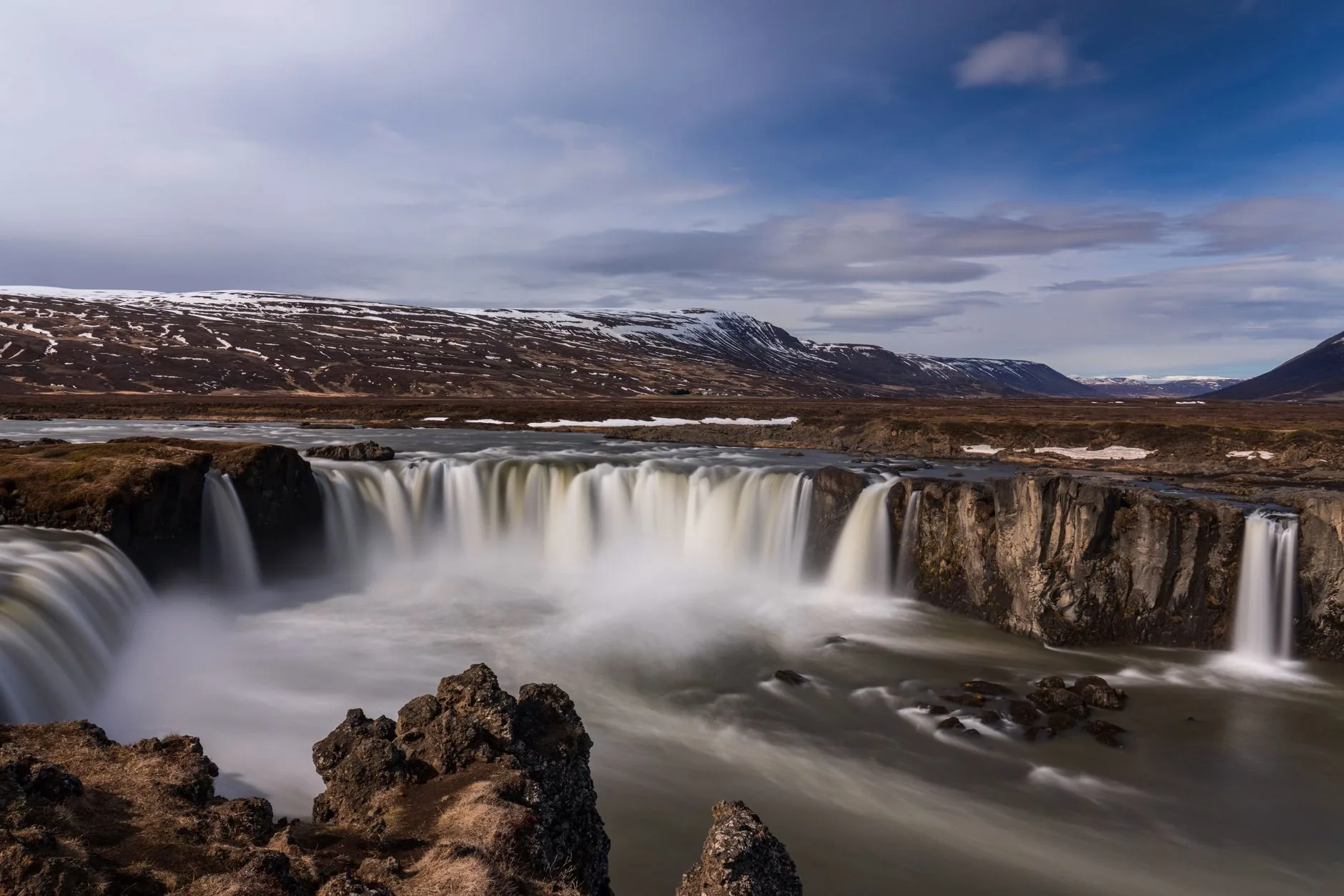 Paysage typique d'Islande avec cascade, montagnes et ciel changeant